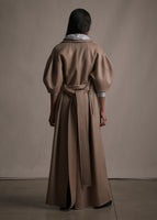 A back-facing image of a model wearing a camel regency coat with short balloon sleeves and a front waist tie.