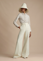 An image taken from further away of a model wearing the Shirt with Thin Bow in Stripe Shirting, styled with the Deeda Pant in Silk Wool and Cleo Hat.