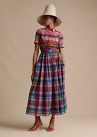 A full body image of a model looking to her right, wearing the Trapeze Shirt in Printed Voile paired with the Cleo Hat and the Lovisa Skirt with Smocked Waist in Printed Voile.