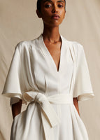 An image of a model from the waist up, wearing an ivory silk v neck sleeved jumpsuit.