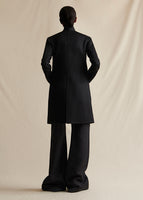 Image of a model wearing a black mid length coat styled over black wide leg pants.