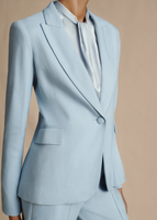 A close up image of a model wearing the Single Breasted Blazer in Stretch Canvas in Pale Blue, paired with the Trouser in Stretch Canvas and Draped Neck Shell in Silk Charmeuse