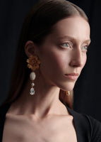 A model wearing gold flower earrings with gem drop downs.