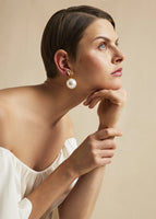 A model wearing large pearl earrings.