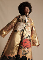 Model is wearing the gold Opera Coat in Jacquard. The Coat is long sleeved and features a large floral design.