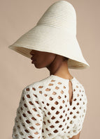 A cropped image of a model wearing an ivory hat with a  ivory cutout short sleeved top.
