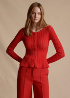 Model is wearing the Cardigan with Peplum in Pointelle Knit in the shade vermillion with the Deeda Pant in Silk Wool. 