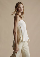 Model is wearing the ivory Cami Top with fringe in silk crepe. Photo shows the side-view of the top, focusing on the fringe. Paired with the ivory Cigarette pant.