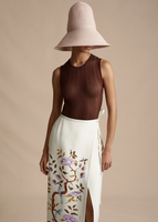 A model wearing the Shell in Metallic Rib, paired with the Cleo Hat and the Wrap Skirt in Printed Silk Wool.
