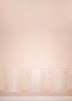 Three crystal cups in front of pale pink background