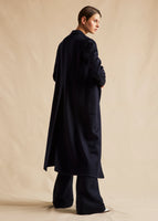 A back-view campaign image of a model in a navy cashmere coat. 
