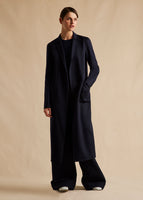 A campaign image of a model in a navy cashmere coat. 