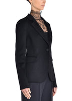 A side angle of a model wearing a black blazer and Chantilly lace turtleneck.