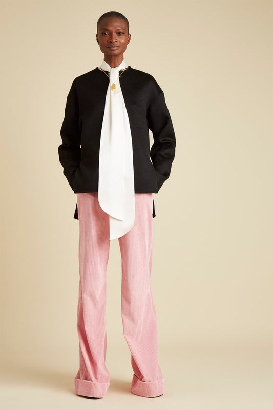 main front image of resort 22, pink trousers with a long bow neck shirt and dark jumper 