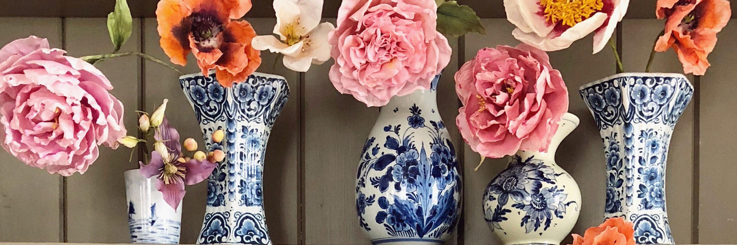 An image of Dutch delftware vases with sugar flowers in them.