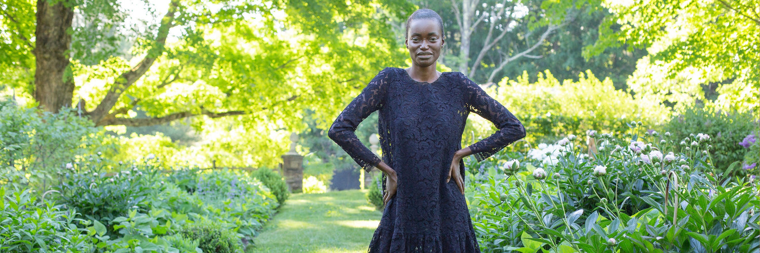 A model standing outdoors wearing a black lace dress.