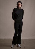 Image of a model facing forwards wearing black crewneck sweater and black crop flare pants.
