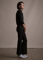 Side image of a model wearing black crewneck sweater and black crop flare pants.