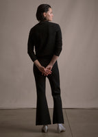 Image of a model facing backwards wearing black crewneck sweater and black crop flare pants.