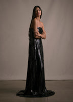Side facing image of model wearing long black floor length sequin strapless busier gown.