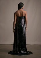 A back-facing image of a model wearing a long black floor length sequin strapless bustier gown. 