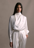 Zoomed in image of model wearing long sleeve silk charmeuse blouse with an asymmetrical wrap front in ivory with matching pants. 