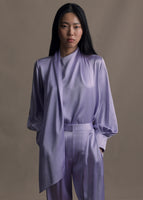 Model wearing long sleeve silk charmeuse blouse with an asymmetrical wrap front worn with matching pants. 