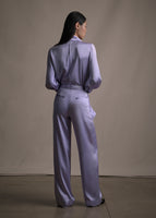 A back-facing image of model wearing a long sleeve silk charmeuse blouse in lavender with matching pants. 