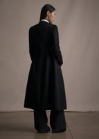 An image of a model standing backwards wearing a black long coat.