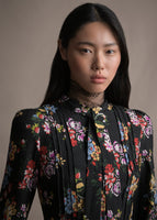 A zoomed in image of a model wearing a lace top under a long sleeved black floral printed dress.