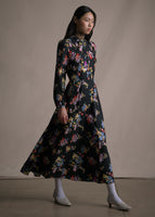 Side angle image of model wearing long sleeved black floral printed mid length dress.