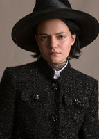 A zoomed in photo of model wearing black jacket with pockets and crystal buttons across the front.