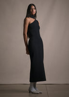A side facing image of model wearing a one shoulder floor length black dress.