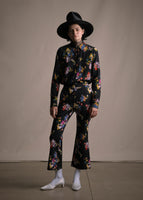 Model wearing a cropped black pant with floral print and a slight flare on the bottom with a matching shirt.