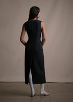 An image of a model facing backwards wearing a black sleeveless sheath dress. 