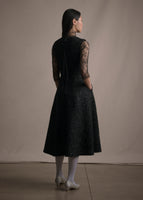 A back-facing image of a model wearing a lace top under a metallic fit and flare dress.
