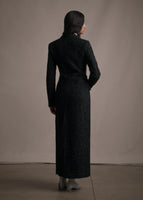 A back-facing image of a model wearing a long black manteau.