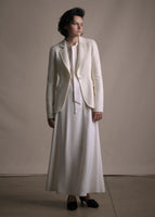 Image of a model wearing an ivory cashmere blazer layered over an ivory silk dress. 