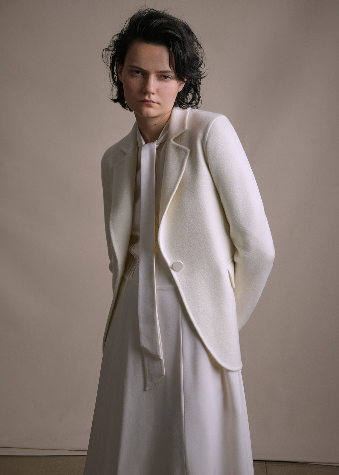 Image of a model wearing an ivory cashmere blazer layered over an ivory silk long dress by Adam Lippes