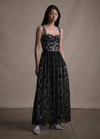 Model facing forward wearing a black lace long sleeveless dress.