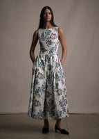A model standing forwards wearing a white floral printed sleeveless long dress.