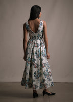 A model facing backwards wearing a white floral printed sleeveless dress with a V in the back.