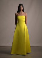 Model facing forward wearing a long yellow gown with skinny straps.