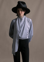 Model wearing striped navy and white long sleeve blouse with an asymmetrical tie-front worn with a hat and black pants. 