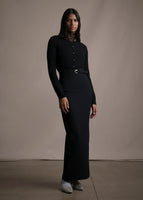Model wearing black sweater and a long black pencil skirt with a black belt and gold buckle.