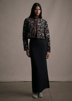 Model wearing an embroidered jacket with long black pencil skirt.