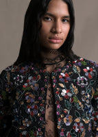 A zoomed in image of the long sleeve front-zip multicolor flower embroidered black bolero detailing with lace top under.