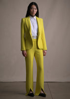 Model wearing long citrine pants with a white shirt and matching citrine blazer.