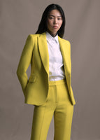 Model wearing a citrine single breasted blazer with two side pockets and a front button and matching citrine pants.