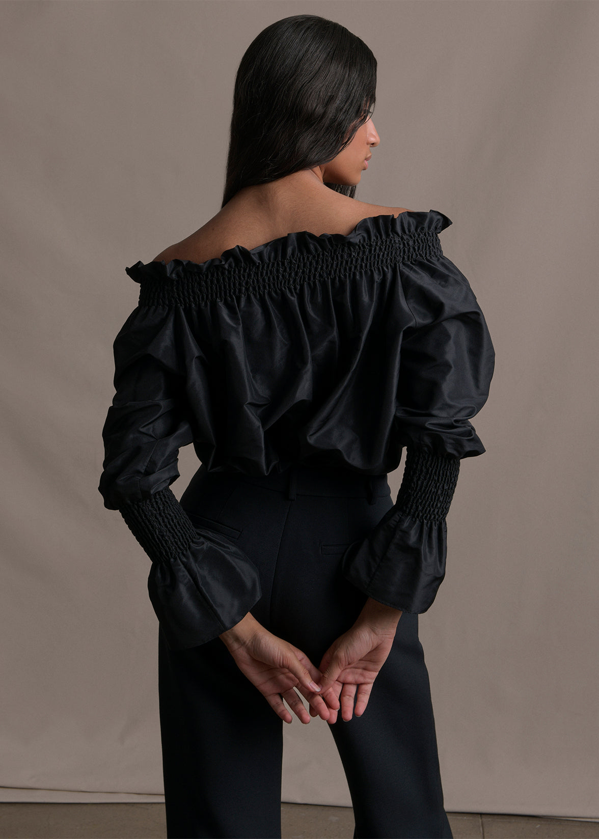 Cropped back image of a black off the shoulder taffeta top.